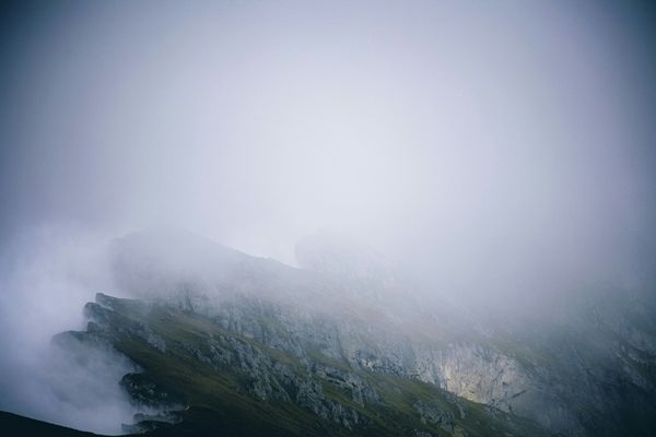 Grey photo of a mountain side covered in mist